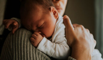A newborn sleeping on their mother's shoulder