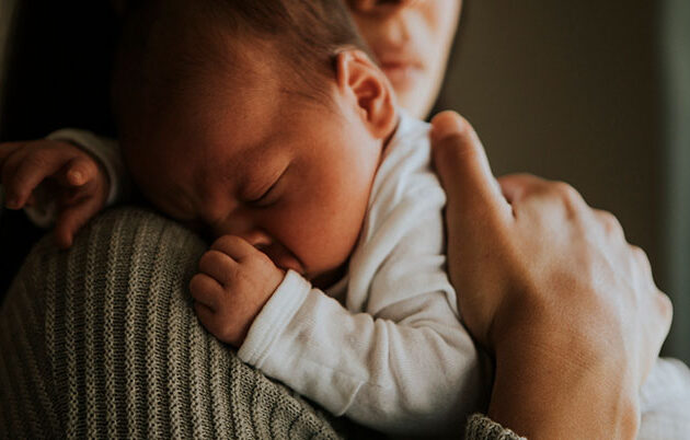 A newborn sleeping on their mother's shoulder