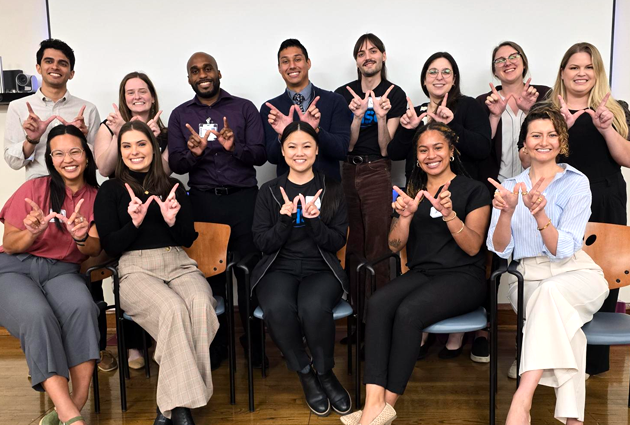 Group of 2024 MD graduates of the TRIUMPH Program (Urban Medicine) make Ws with their hands