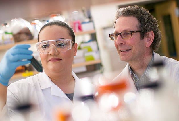 Dr. Bruce Klein and Nydiaris Hernandez look at a sample in a bioreactor tube