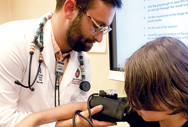 MD student Jacob Jones places a blood pressure cuff on a child