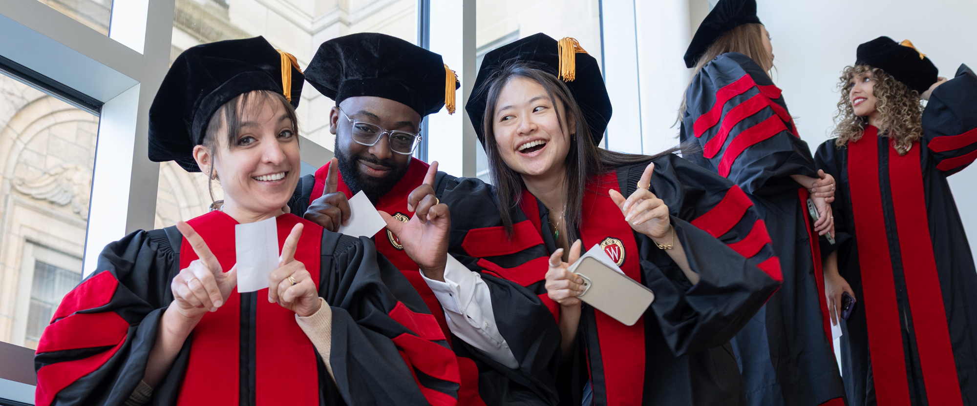 Group of smiling 2025 MD graduates make the letter W with their hands