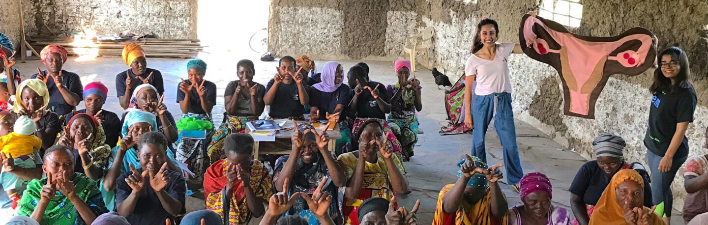 Two women present a fabric model representing women's health to promote global health education to a large group of people