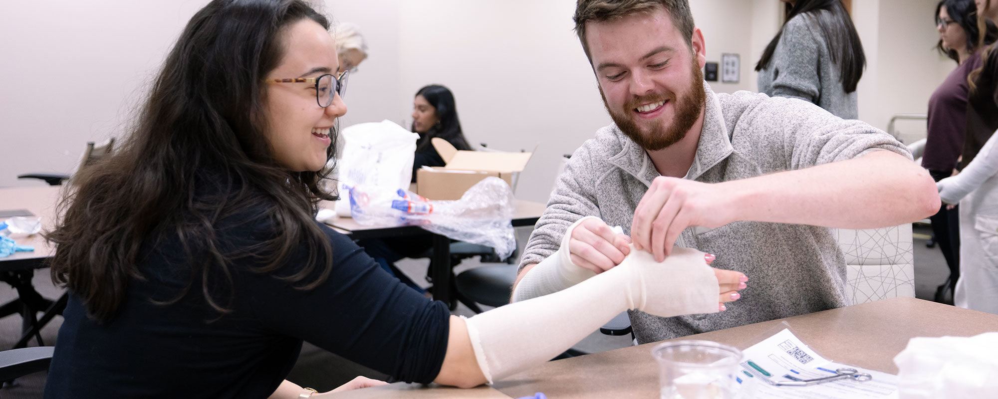 A student wraps another students arm in a bandage at the annual Family Medicine Procedures Fair