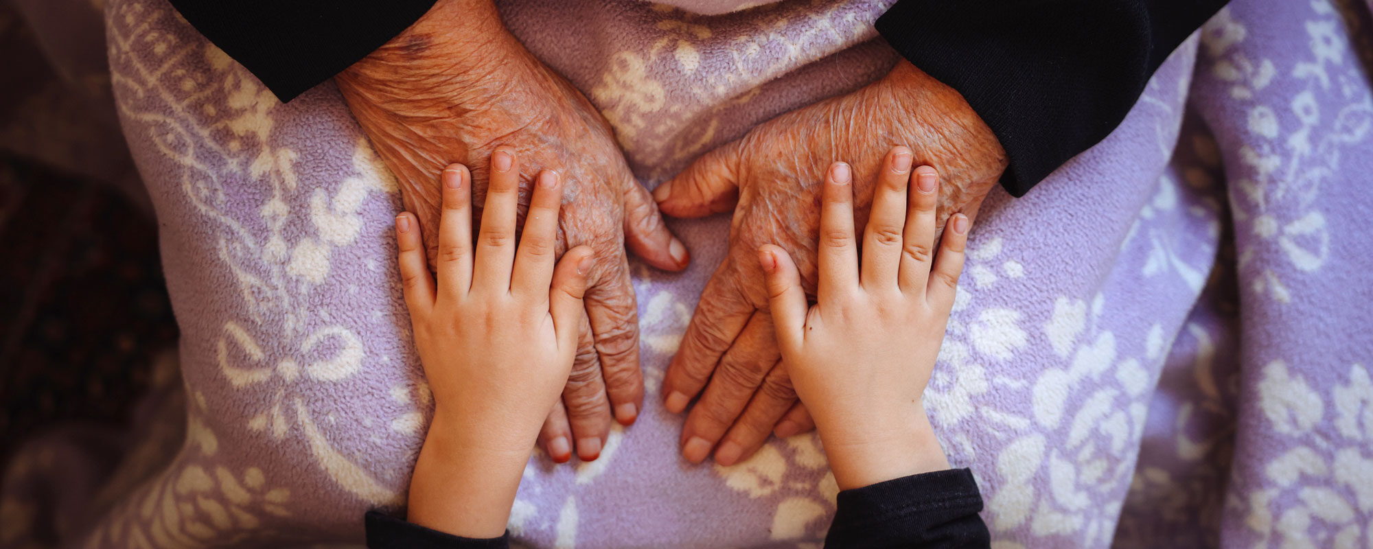A child's hands placed on top of older adult hands