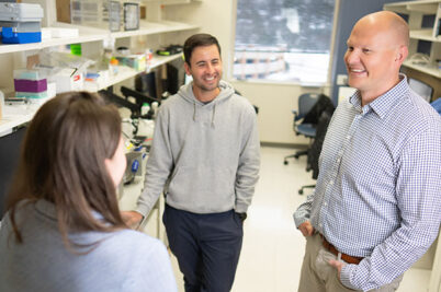 Christopher Sundberg talks with two research team members in his lab.