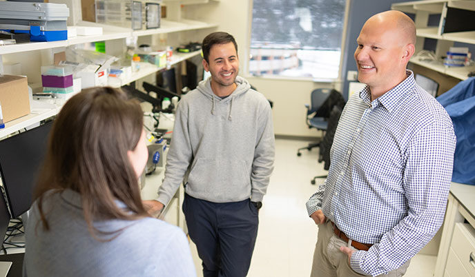 Christopher Sundberg talks with two research team members in his lab.