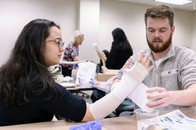 A student wraps another students arm in a bandage at the annual Family Medicine Procedures Fair.