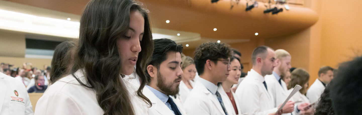 Students in white coats read the Declaration of Geneva