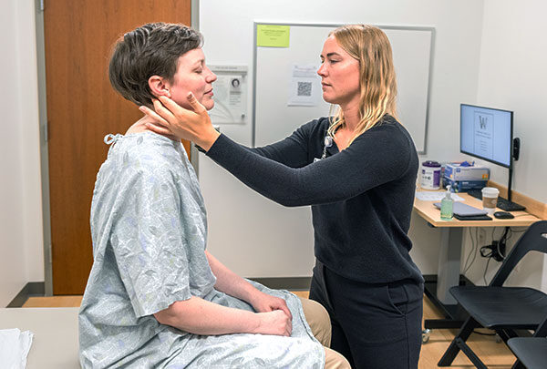 A student feels both sides a patient's neck with their hands