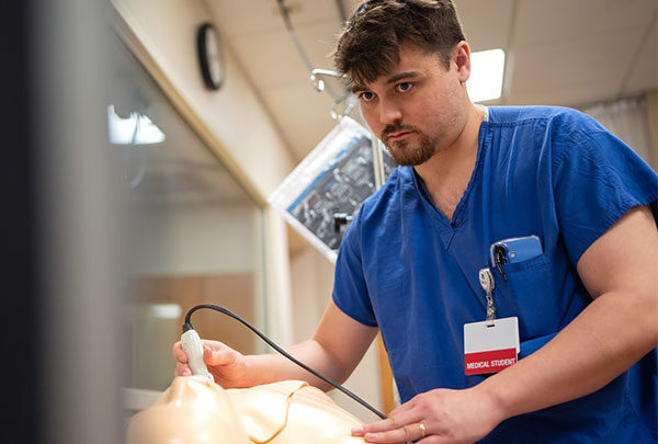 A medical student practices an ultrasound on a manikin