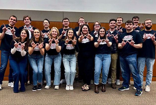 Students smiling together, each making a 'W' with their hands
