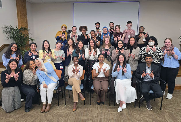 Students smiling in a big group, each making a 'W' with their hands