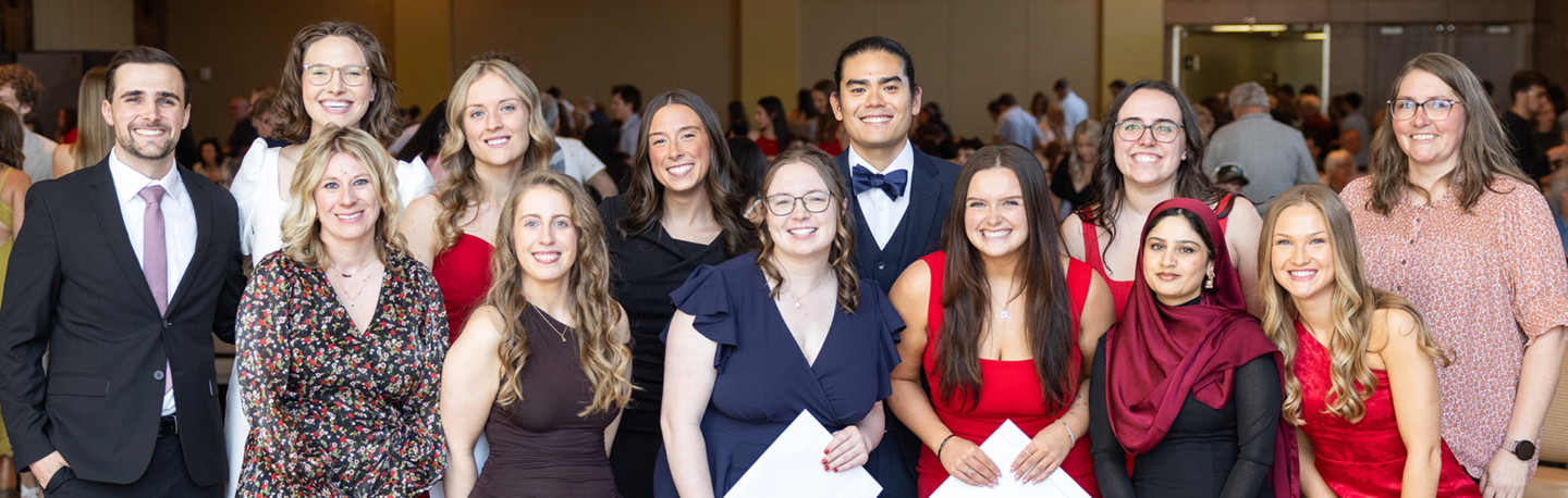 A large group of students in dress attire stand together and smile