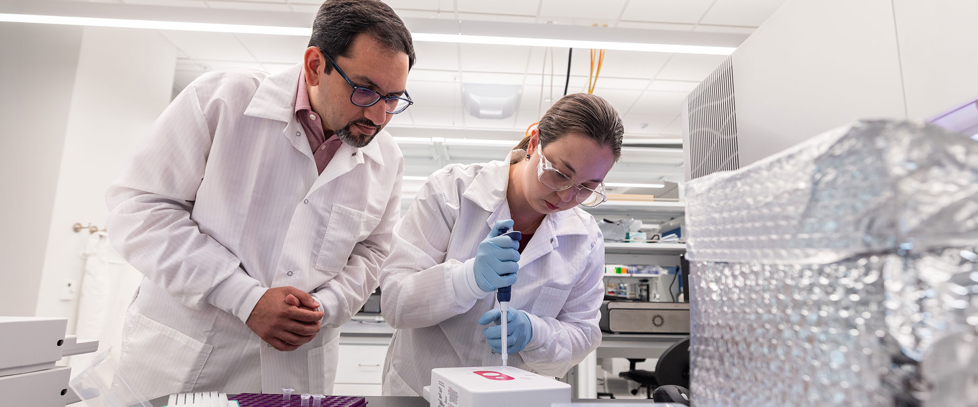 Muhammed Murtaza, PhD, and fellow scientist using a pipette in the lab
