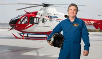 Emergency medicine doctor Michael Abernethy standing in front of a medical helicopter