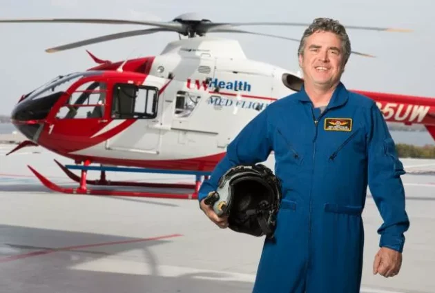 Emergency medicine doctor Michael Abernethy standing in front of a medical helicopter