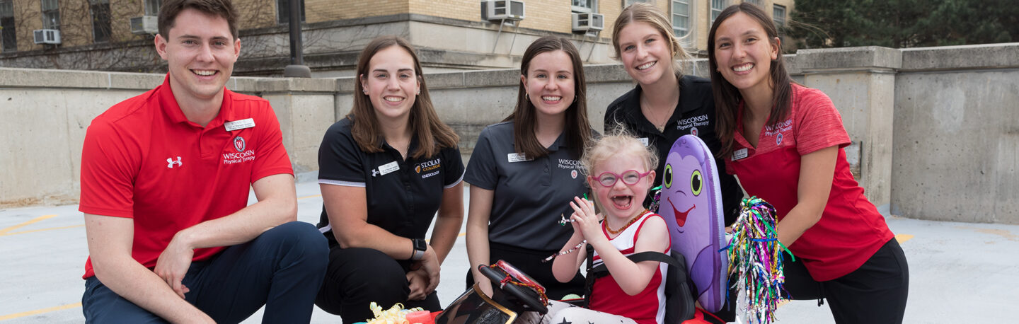 A group of students provide a very happy child with a mini car