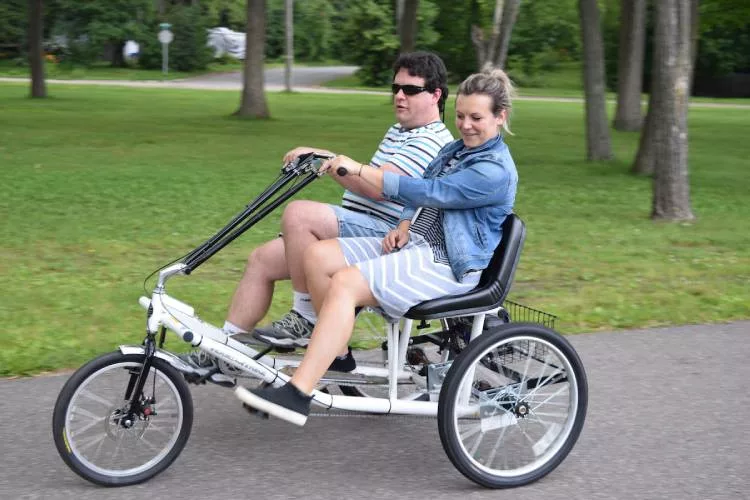 Two people pedaling a three-wheel, two-passenger trike